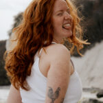 Eine rothaarige Frau mit dem Rücken zugeneigt lacht zur rechten Serite