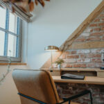 Ein Stuhl an einem Arbeitstisch auf dem eine Schreibtischlampe an ist.