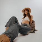 Eine Frau mit großem Hut liegt auf dem Boden und streckt den Fuß in die Kamera