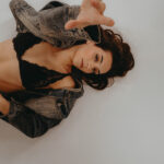 Eine Frau im BH liegt auf dem Boden und schaut in die Kamera.