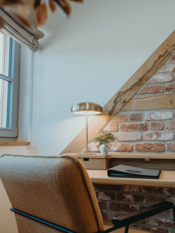 Ein Stuhl an einem Arbeitstisch auf dem eine Schreibtischlampe an ist.