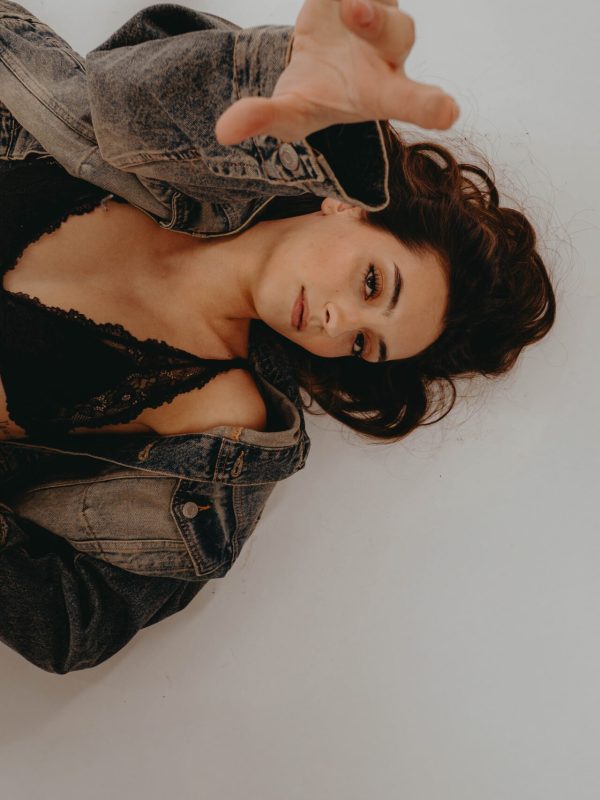 Eine Frau im BH liegt auf dem Boden und schaut in die Kamera.